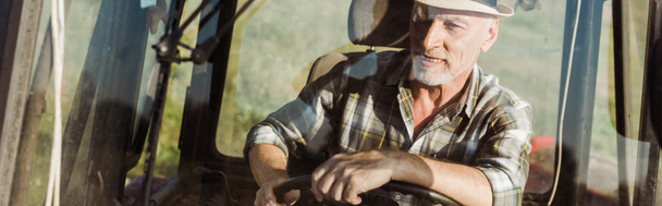 panoramic shot of self-employed farmer in straw hat driving tractor  - Photo, Image