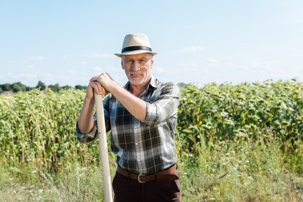 ευτυχισμένος αγρότης κρατώντας τσουγκράνα και χαμογελά στο πεδίο  - Φωτογραφία, εικόνα