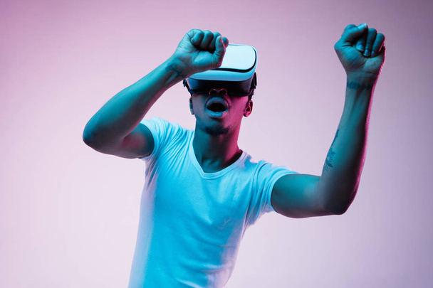 Young african-american mans using VR-glasses in neon light - Fotoğraf, Görsel