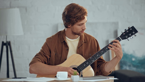 gefocuste Redhead man speelt akoestische gitaar thuis - Video