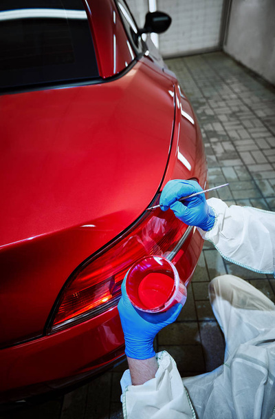 Defectos de tintura de una pintura roja del coche en el servicio
 - Foto, imagen