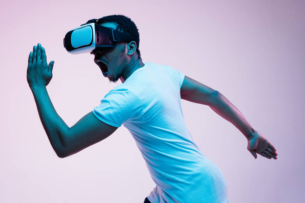 Young african-american mans using VR-glasses in neon light - Foto, Imagen