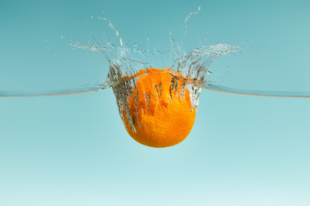fresh orange falling in water with splash on blue background - Fotoğraf, Görsel