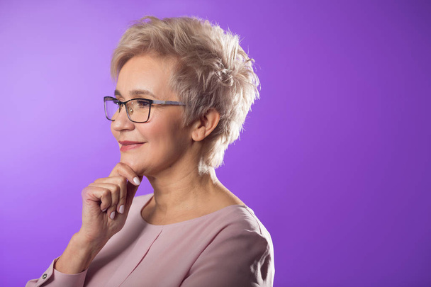 portrait of adult woman in glasses with short haircut on purple background - Foto, Imagen