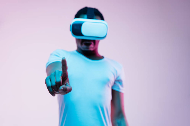 Young african-american mans using VR-glasses in neon light - Fotó, kép
