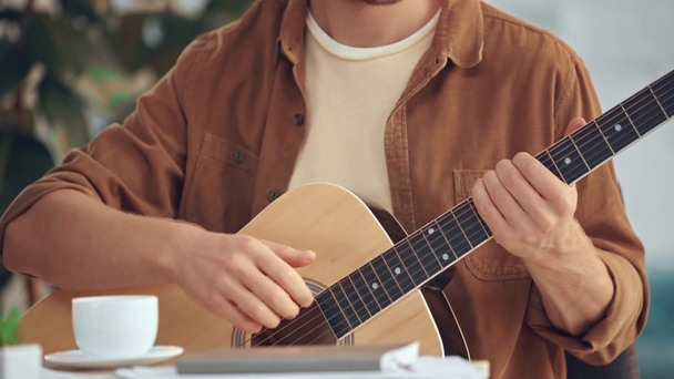 bijgesneden beeld van de man die akoestische gitaar speelt en koffie drinken - Video