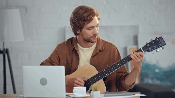 μουσικός παίζει ακουστική κιθάρα κατά τη διάρκεια συνομιλίας βίντεο στο laptop - Πλάνα, βίντεο