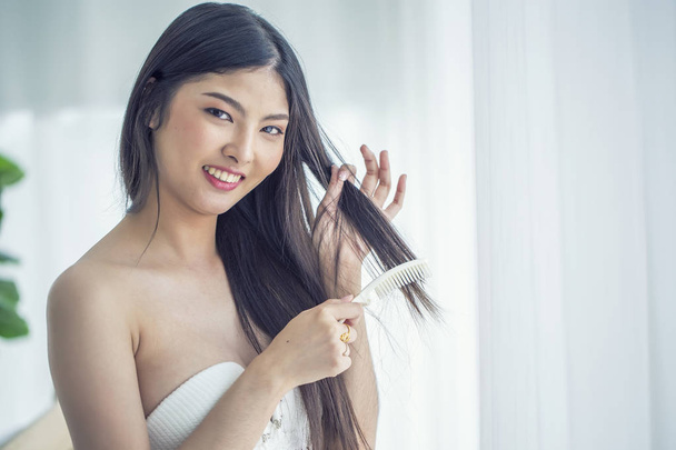 Charming Asian woman wearing bra combing hair - Photo, Image