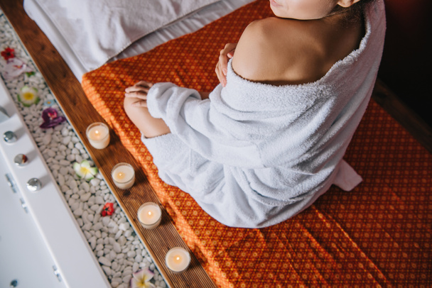 cropped view of woman in bathrobe sitting on massage mat in spa salon - Фото, зображення