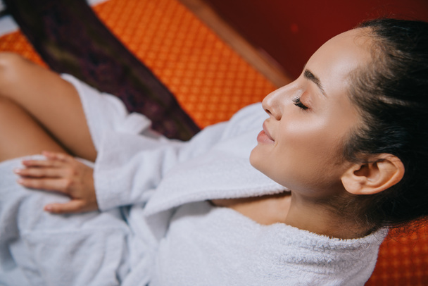 high angle view of attractive woman in bathrobe sitting on massage mat in spa salon - Fotó, kép