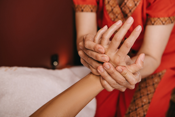 обрізаний вид масажиста робить масаж рук жінці в спа-салоні
  - Фото, зображення