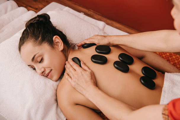 vue recadrée du masseur faisant massage aux pierres chaudes à la femme dans le salon de spa
  - Photo, image