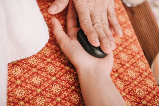 vista recortada de masajista haciendo masaje de piedra caliente a la mujer en el salón de spa
  - Foto, Imagen
