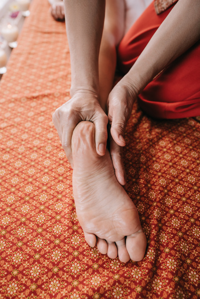 cropped view of masseur doing foot massage to woman in spa salon  - Fotografie, Obrázek