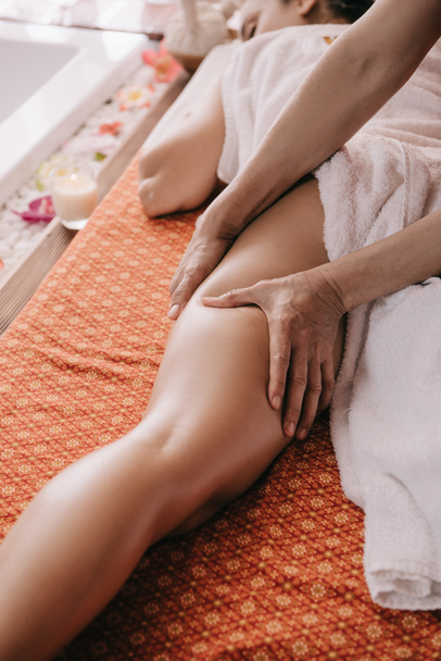 cropped view of masseur doing foot massage to woman in spa salon  - Fotografie, Obrázek