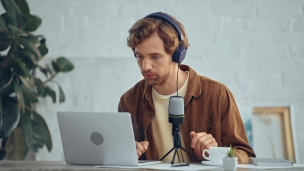 άνθρωπος στα ακουστικά με μικρόφωνο εκπέμπει κατά τη χρήση του φορητού υπολογιστή - Πλάνα, βίντεο
