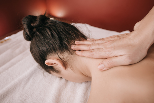 cropped view of masseur doing neck massage to woman in spa salon  - Fotó, kép