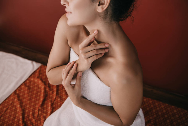 обрізаний вид жінки в білому рушнику, що сидить на масажному килимку
  - Фото, зображення