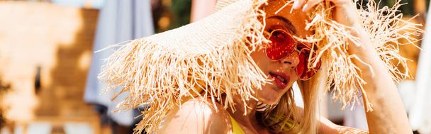 πανοραμική βολή ελκυστική γυναίκα με γυαλιά ηλίου και ψάθινο καπέλο - Φωτογραφία, εικόνα