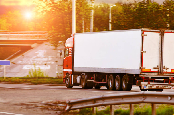 Kırsal yolda gün batımında gökyüzüne karşı yazı için yeri olan beyaz karavanlı kırmızı bir kamyon. - Fotoğraf, Görsel