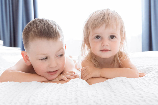 Screen Portrait of a Brother and Sister in a White Bed. Childhood concept - Φωτογραφία, εικόνα