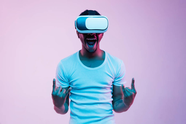 Young african-american mans using VR-glasses in neon light - Foto, imagen