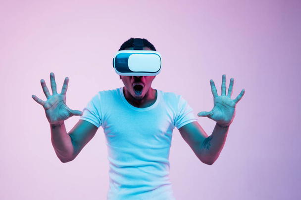 Young african-american mans using VR-glasses in neon light - Foto, Imagem