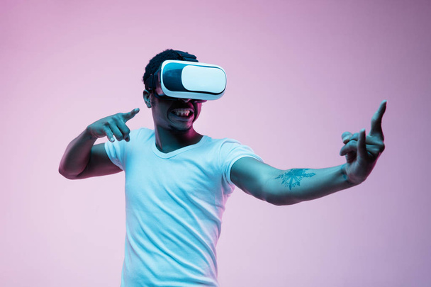 Young african-american mans using VR-glasses in neon light - Foto, afbeelding