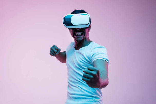 Fiatal afro-amerikai Mans segítségével VR-szemüveg a Neonfény - Fotó, kép