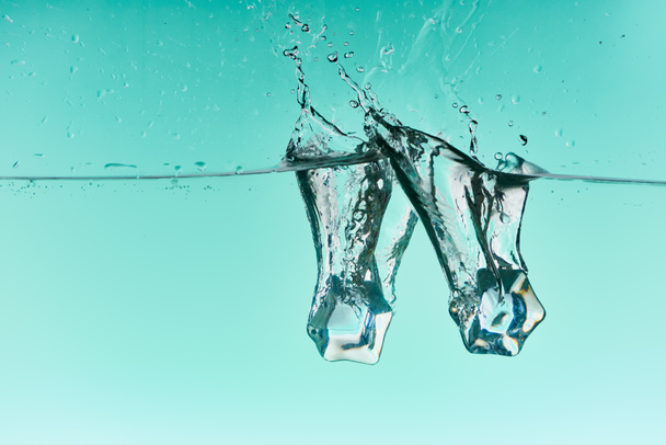 ice cubes falling in water with splash on turquoise background - Foto, immagini