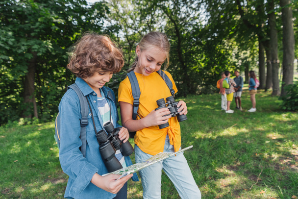 selective focus of happy kids with binoculars looking at map  - Foto, Imagen