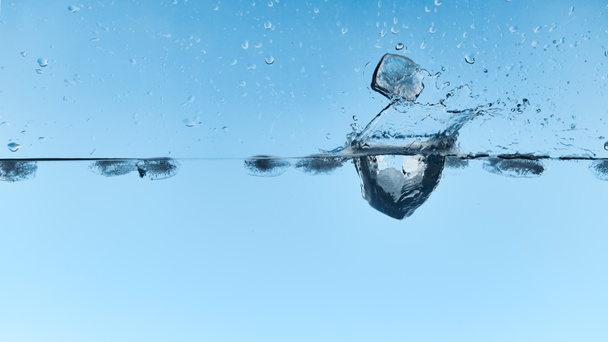 transparant water met vallende ijsblokjes en Splash op blauwe achtergrond - Foto, afbeelding