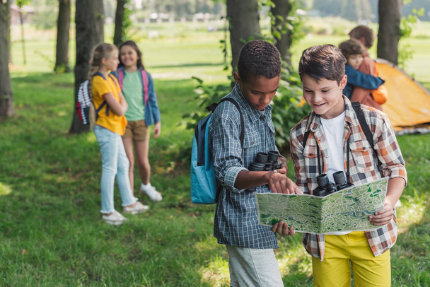 selective focus of african american kid looking at map near friend  - Photo, Image