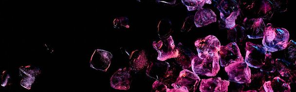 panoramiczny strzał przezroczystych kostek lodu z fioletowym światłem na czarno - Zdjęcie, obraz