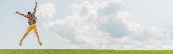 Panoramaaufnahme eines Jungen, der gegen den blauen Himmel springt und gestikuliert  - Foto, Bild