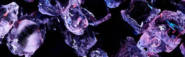 panoramic shot of transparent ice cubes with purple lighting isolated on black - Photo, Image