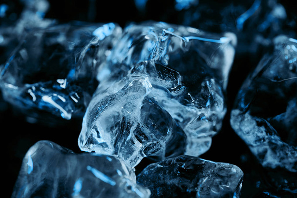 close up view of frozen ice cubes with blue lighting isolated on black - Photo, Image