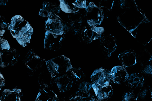 vista superior de cubos de gelo transparentes congelados com iluminação azul isolada em preto
 - Foto, Imagem