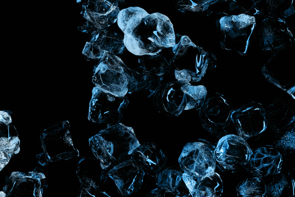 top view of frozen clear ice cubes with blue lighting isolated on black - Photo, Image