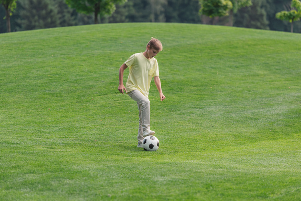 cute boy playing football on green grass  - Фото, изображение