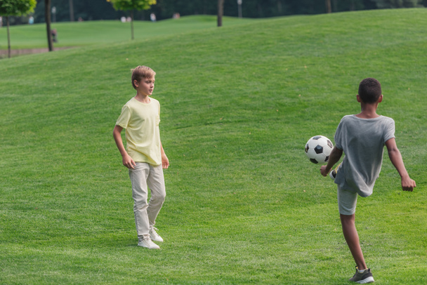 cute multicultural kids playing football on grass  - Photo, Image