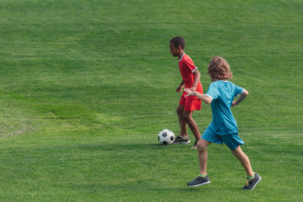 aranyos multikulturális gyerekek focizni a füvön  - Fotó, kép