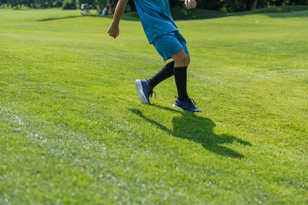 cropped view of kid running on green grass  - Zdjęcie, obraz