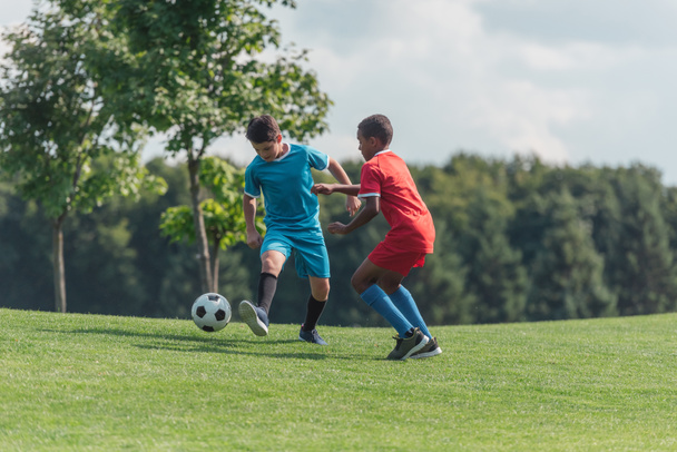 cute multicultural children playing football on grass  - Zdjęcie, obraz