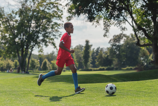 cute african american kid playing football on grass  - Фото, зображення