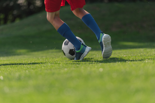 vue recadrée du gamin en tenue de sport courir sur l'herbe verte avec le football
  - Photo, image