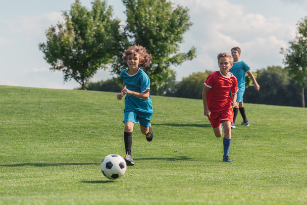 happy kids running while playing football outside  - Fotoğraf, Görsel