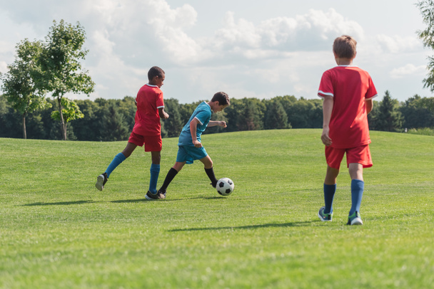 niños multiculturales y lindos jugando al fútbol afuera
  - Foto, Imagen