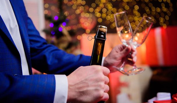 Lets celebrate. Male hands opening champagne bottle pouring glasses christmas decorations background. Drink champagne or sparkling wine. Celebrate new year with champagne. Toast and cheers concept - Photo, Image