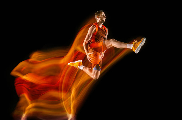 Young caucasian basketball player against dark background in mixed light - Foto, Imagem